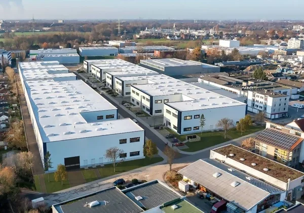 Eine große, weiße Siedlung von Mehrfamilienhäusern mit Flachdächern in der Abenddämmerung.