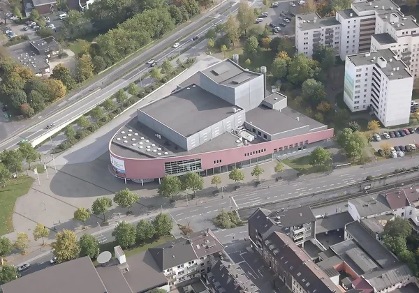 Ein Stadtteil, der ein halbrundes, großes Gebäude sowie mehrere weiße Hochhäuser und zwei große Straßen aus der Vogelperspektive zeigt.